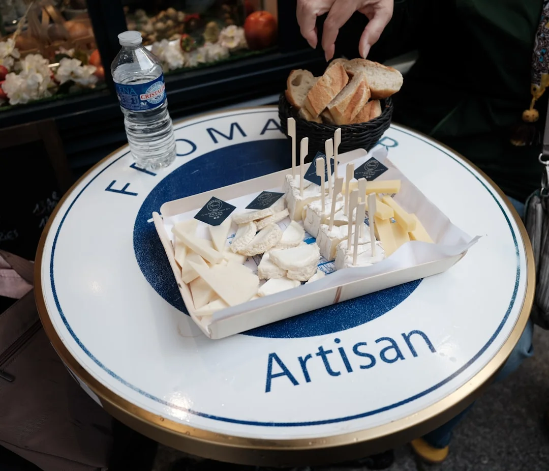 An abundant cheese and charcuterie gift basket overflowing with aged cheddar, cured salami, artisan crackers, and a small pot of honeycomb on a rustic wooden surface